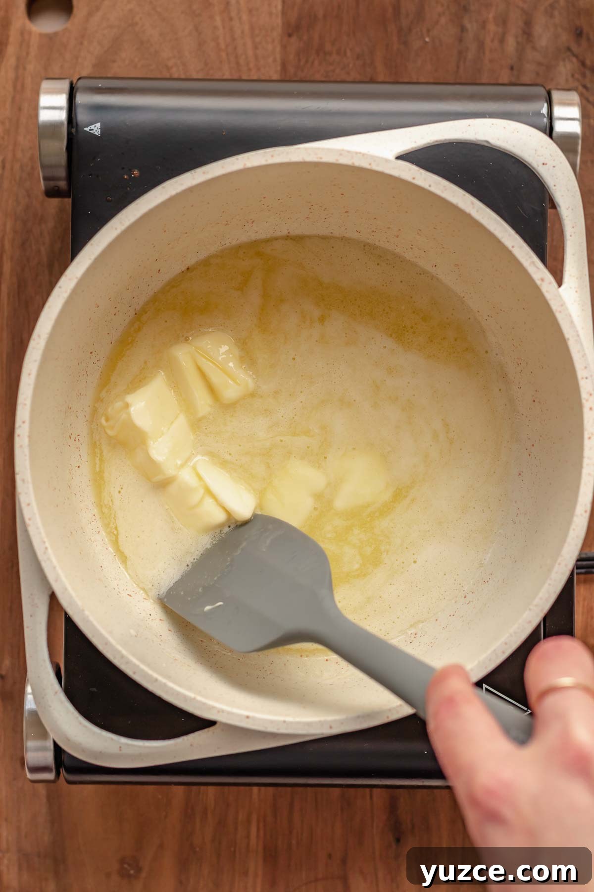 Salted Bourbon Caramel Candies: Sticky Sweet Whiskey Caramels 4 A spatula stirs melting butter in a pot.