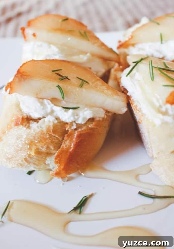 Sweet Pepper Jelly and Cream Cheese Dip Recipe for Entertaining 8 Close-up of sliced baguette topped with a layer of goat cheese, pear slices, fresh herbs, and drizzled with honey, creating a delectable goat cheese crostini on a white plate.