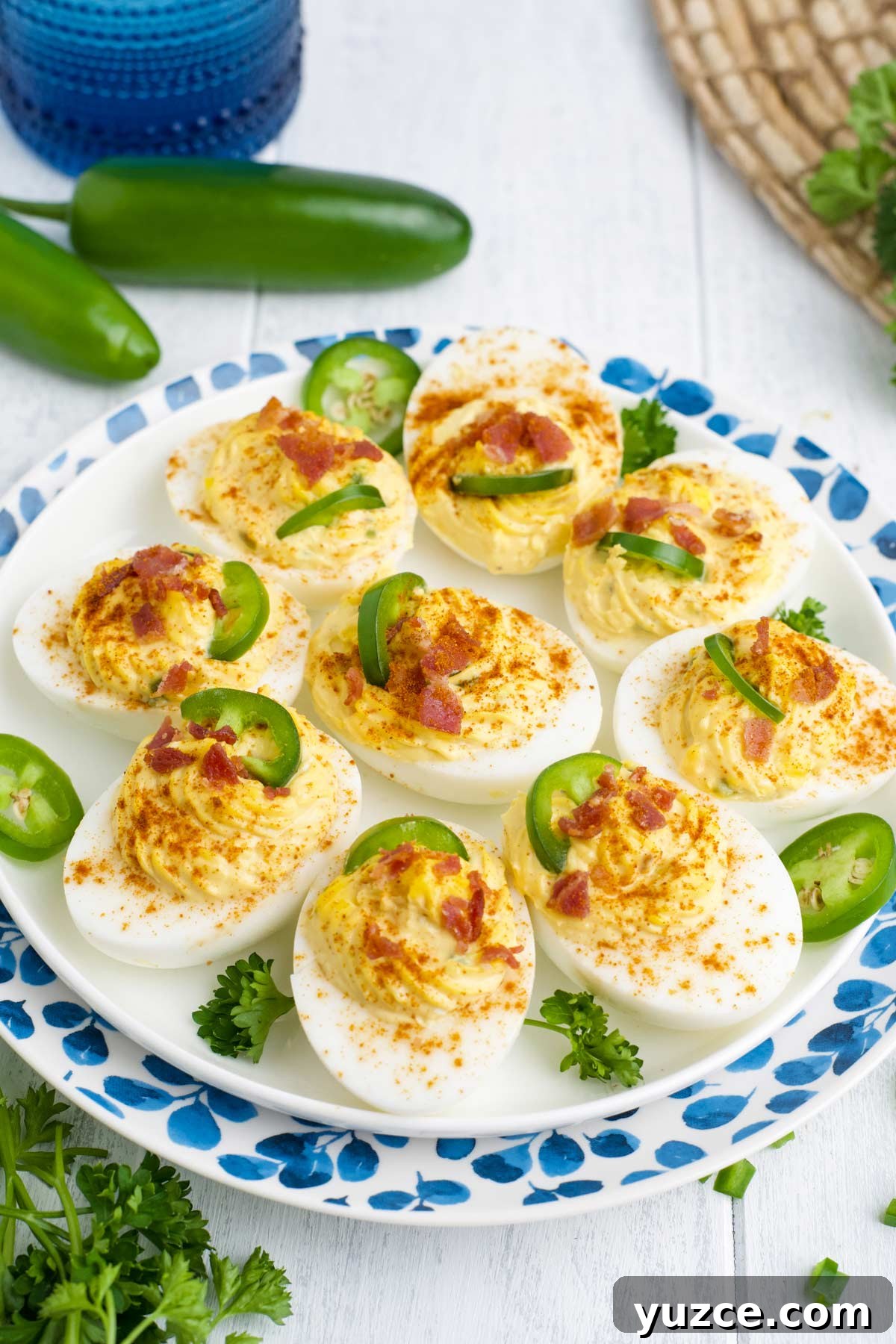 Jalapeño Bacon Deviled Eggs: Spicy Party Appetizer Recipe 2 Spicy deviled eggs on blue and white plate.