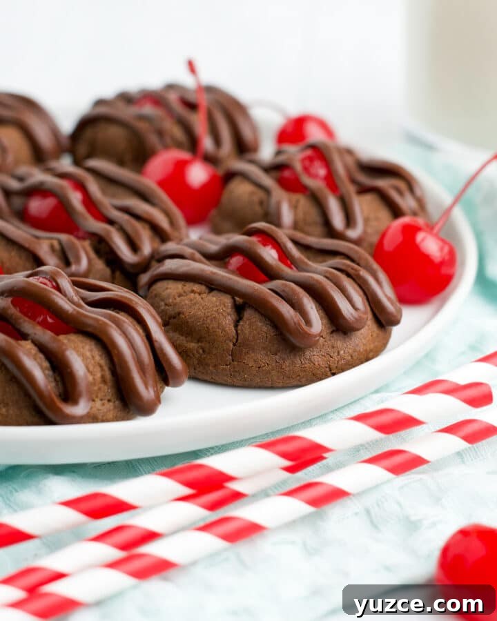 White plate of chocolate cherry cookies on the table with red and white straws in front.