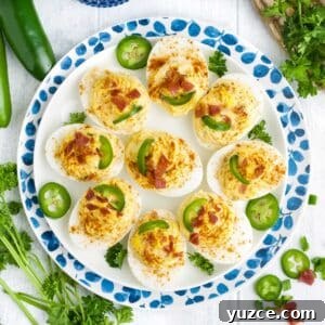 Jalapeño Bacon Deviled Eggs: Spicy Party Appetizer Recipe 11 Jalapeno deviled eggs on a plate garnished with jalapeno slices.