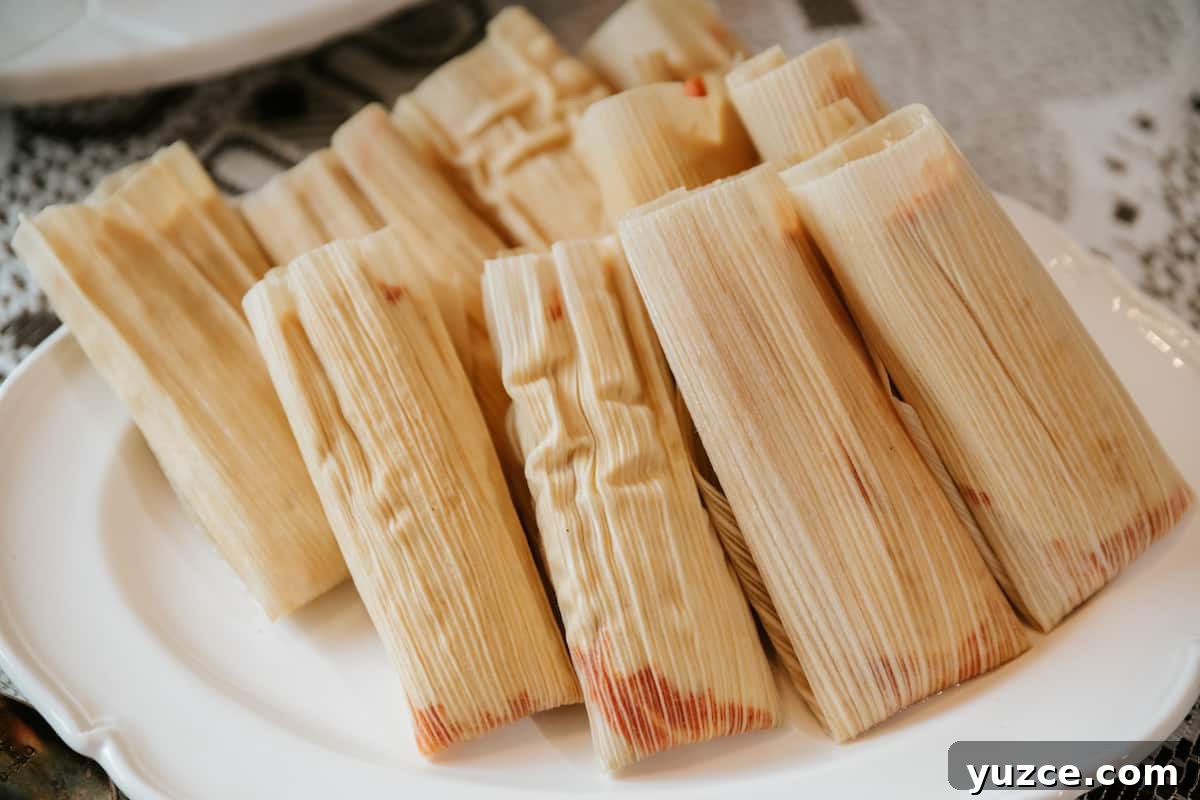 How to Host a Tamalada: Step-by-Step Tamal-Making Party Guide 9 a big stack of rolled tamales on a white plate prior to steaming.
