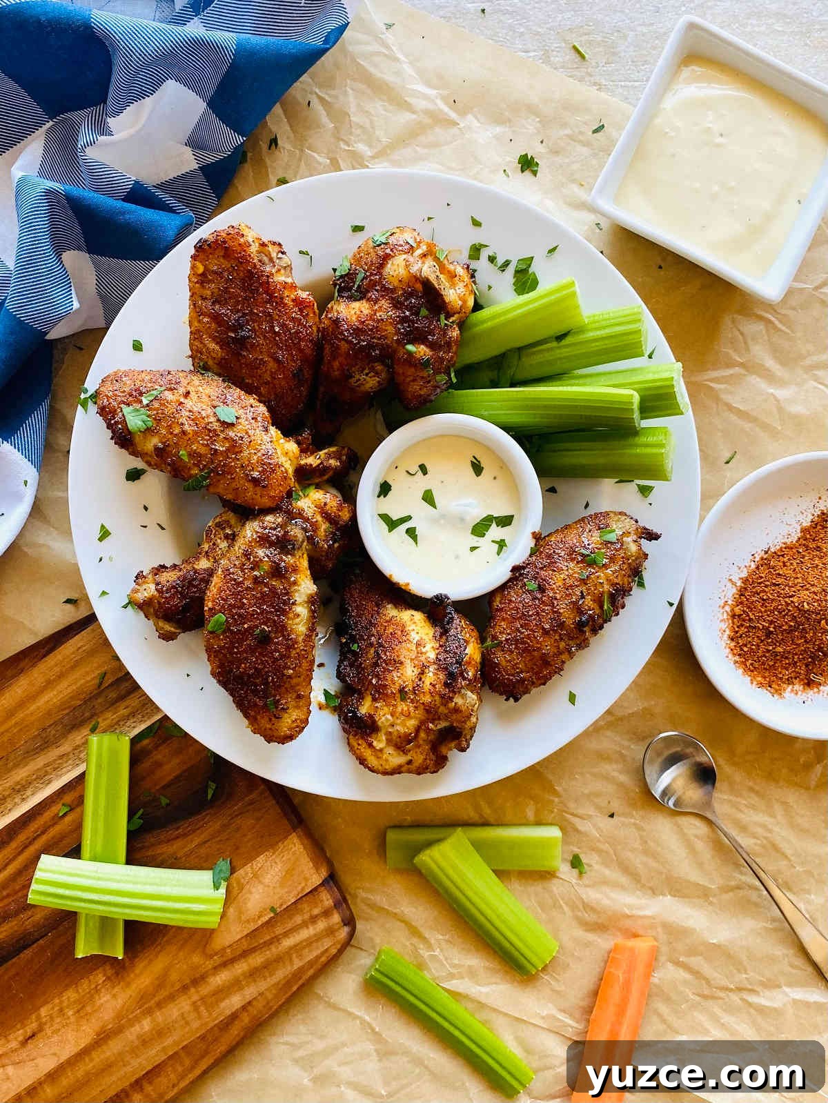 Crispy Cajun Chicken Wings Recipe: Spicy Oven-Baked Wings 2 cajun wings on a plate with dish of blue cheese, celery and carrots