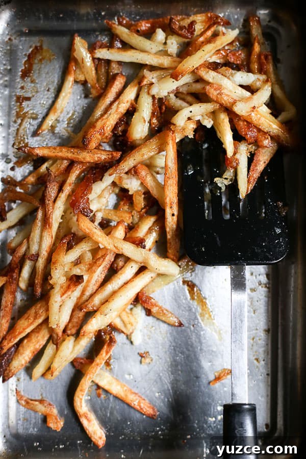 Crispy Gluten-Free Fish and Chips Recipe for Home Cooking 7 chips in a roasting dish with a spatula