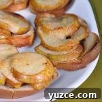 Oblique close up of a batch of maple pear crostini on a white ceramic platter sitting on a green wooden table | Foodal