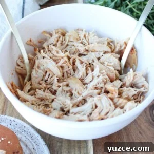 Bowl of air fryer shredded chicken with two forks.