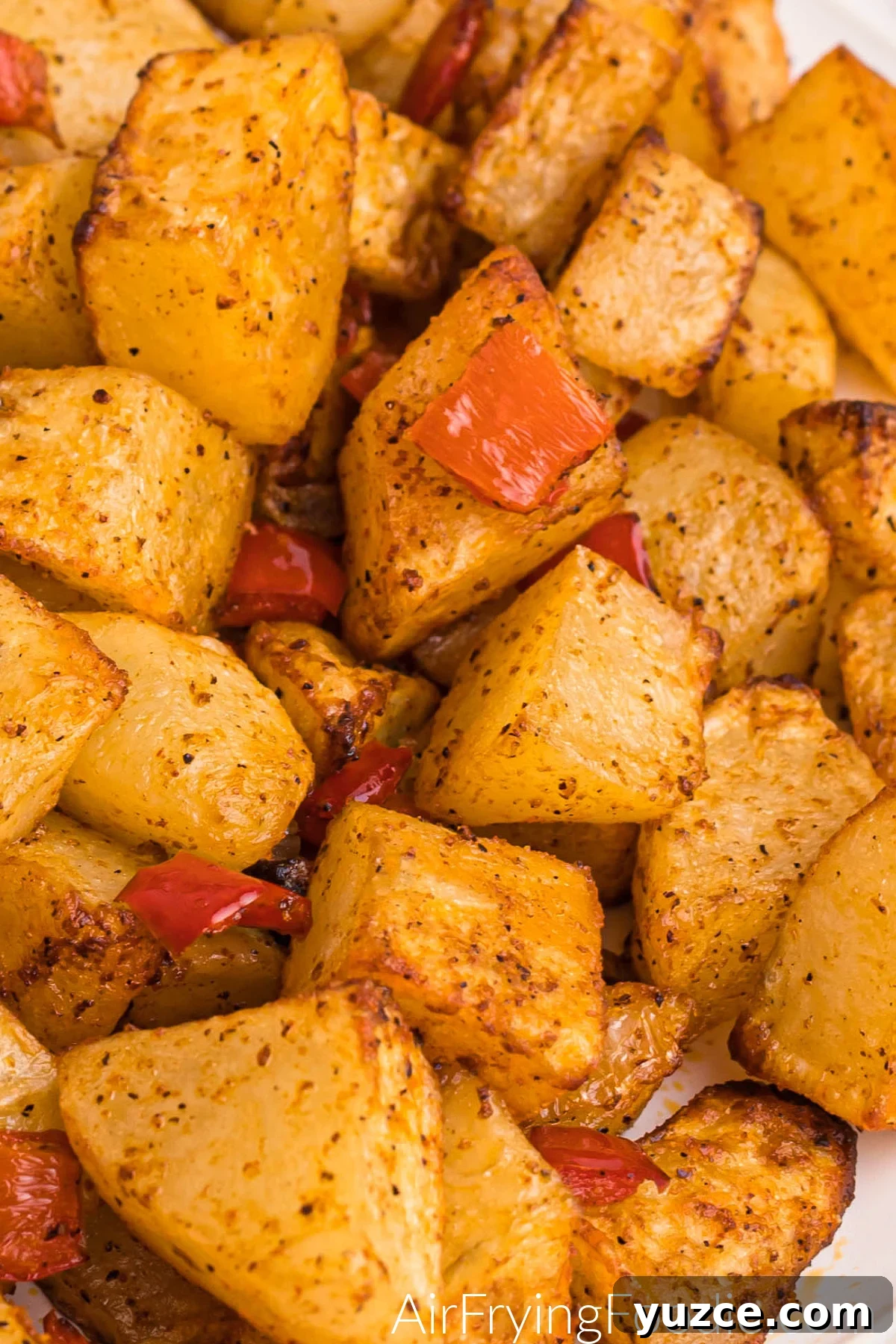 Crispy Air Fryer Home Fries Recipe for Breakfast or Brunch 11 Air fried, cubed, and cooked russet potatoes with onion and bell pepper on a white plate, ready to serve.
