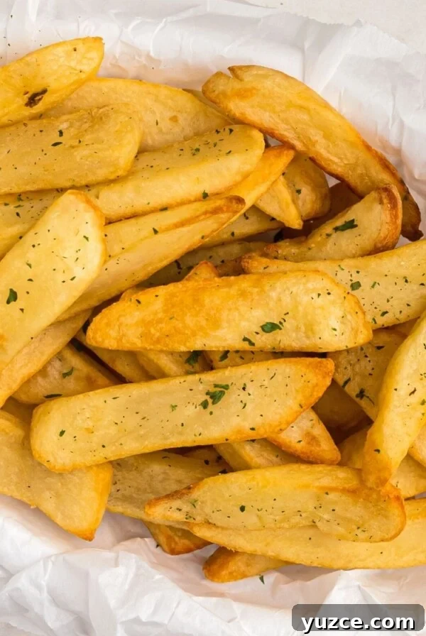 Crispy Air Fryer Home Fries Recipe for Breakfast or Brunch 15 Air fryer steak fries in a basket, garnished with parsley flakes.