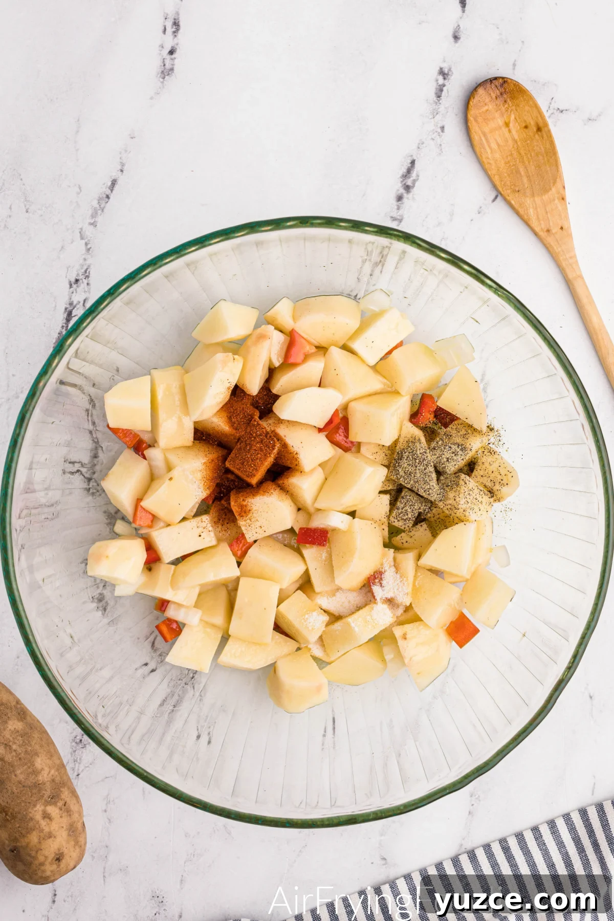 Crispy Air Fryer Home Fries Recipe for Breakfast or Brunch 6 Seasonings in the bowl with potatoes, ready to be combined.