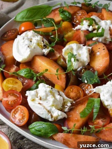 Angled view of tomato and burrata salad on a round plate.