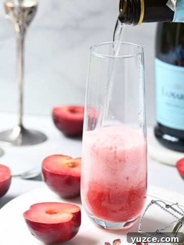 Prosecco being poured into a glass with plum puree.