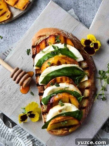 Overhead view of toast with grilled peaches layered with mozzarella, basil and balsamic on a grey cutting board