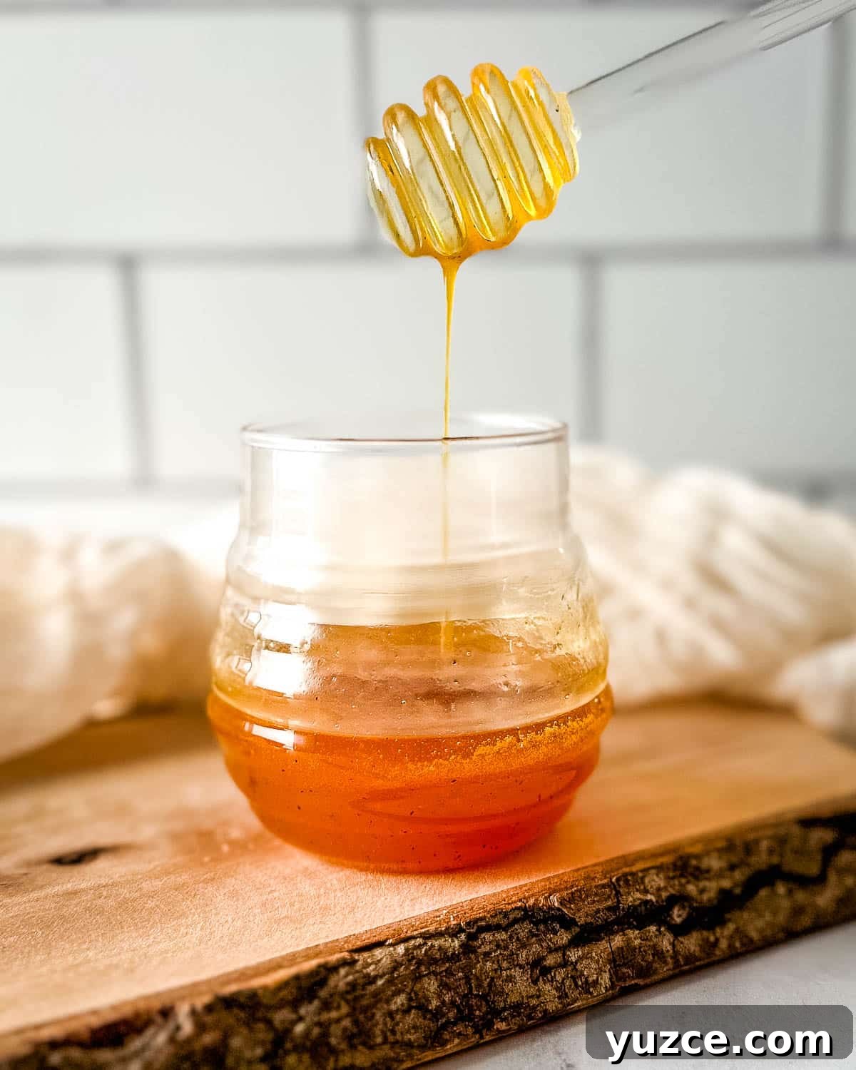Homemade Hot Honey Sauce Recipe for Spicy-Sweet Dishes 8 Hot honey sauce is drizzled into a glass jar with a glass honey dipper.
