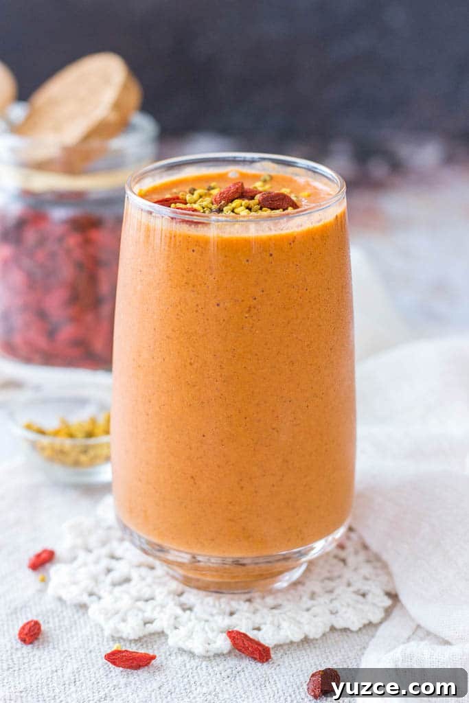 Goji Berry Smoothie served in a tall glass topped with goji berries and bee pollen