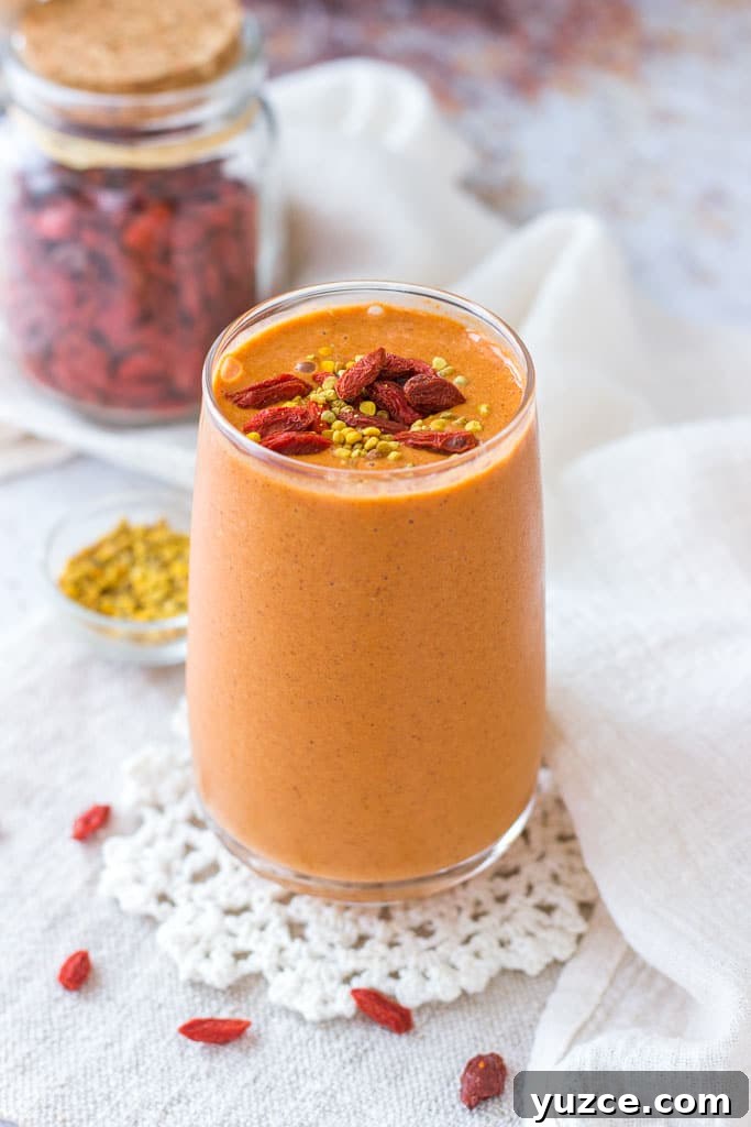 Goji Berry Smoothie served in a tall glass topped with goji berries and bee pollen