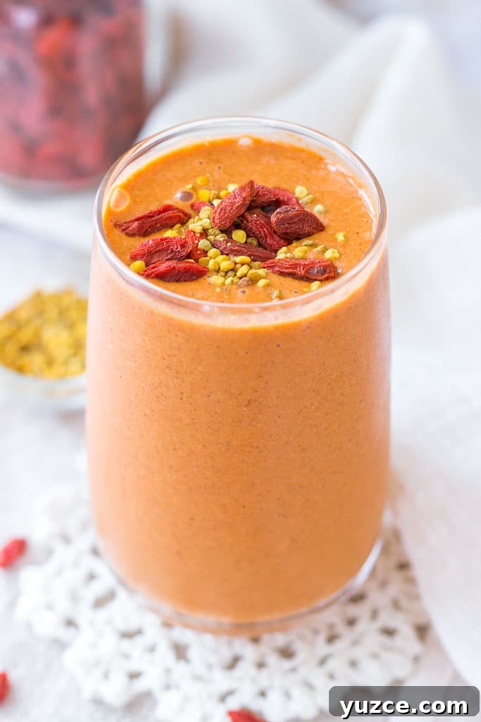 Goji Berry Smoothie served in a tall glass topped with goji berries and bee pollen