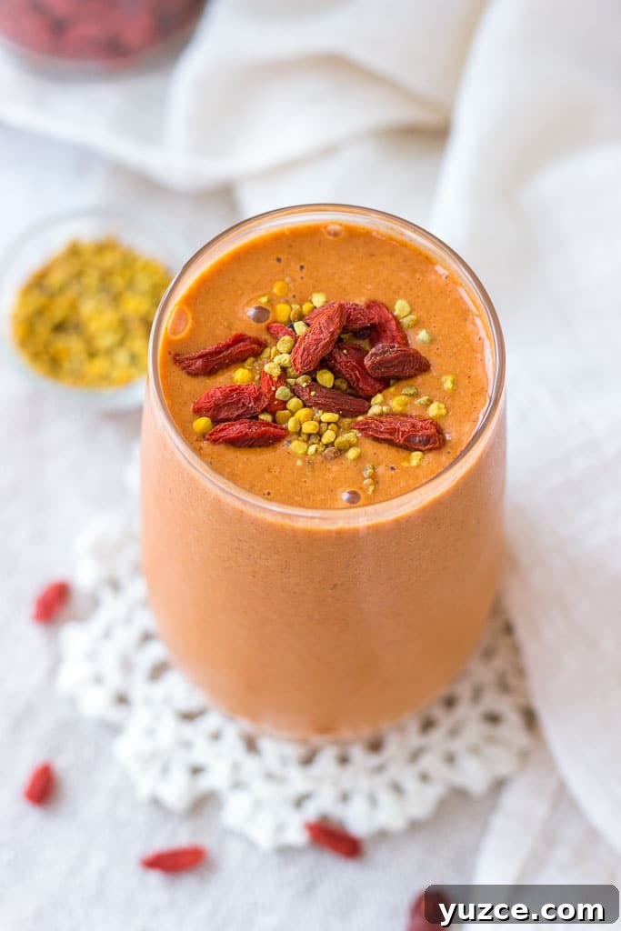 Goji Berry Smoothie served in a tall glass topped with goji berries and bee pollen