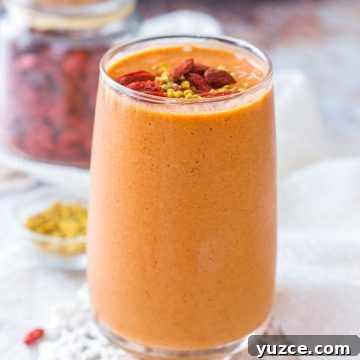 Goji Berry Smoothie served in a tall glass topped with goji berries and bee pollen