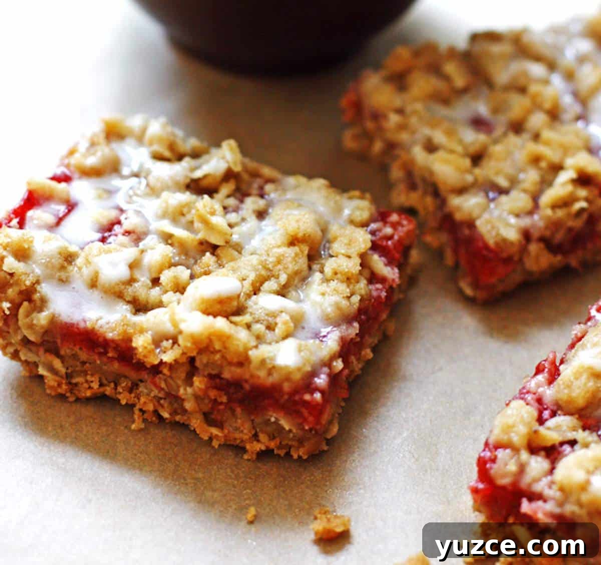 Strawberry Rhubarb Crumble Bars Recipe — Sweet Tart Dessert Bars 8 Three slices of glazed strawberry rhubarb crumble bars.