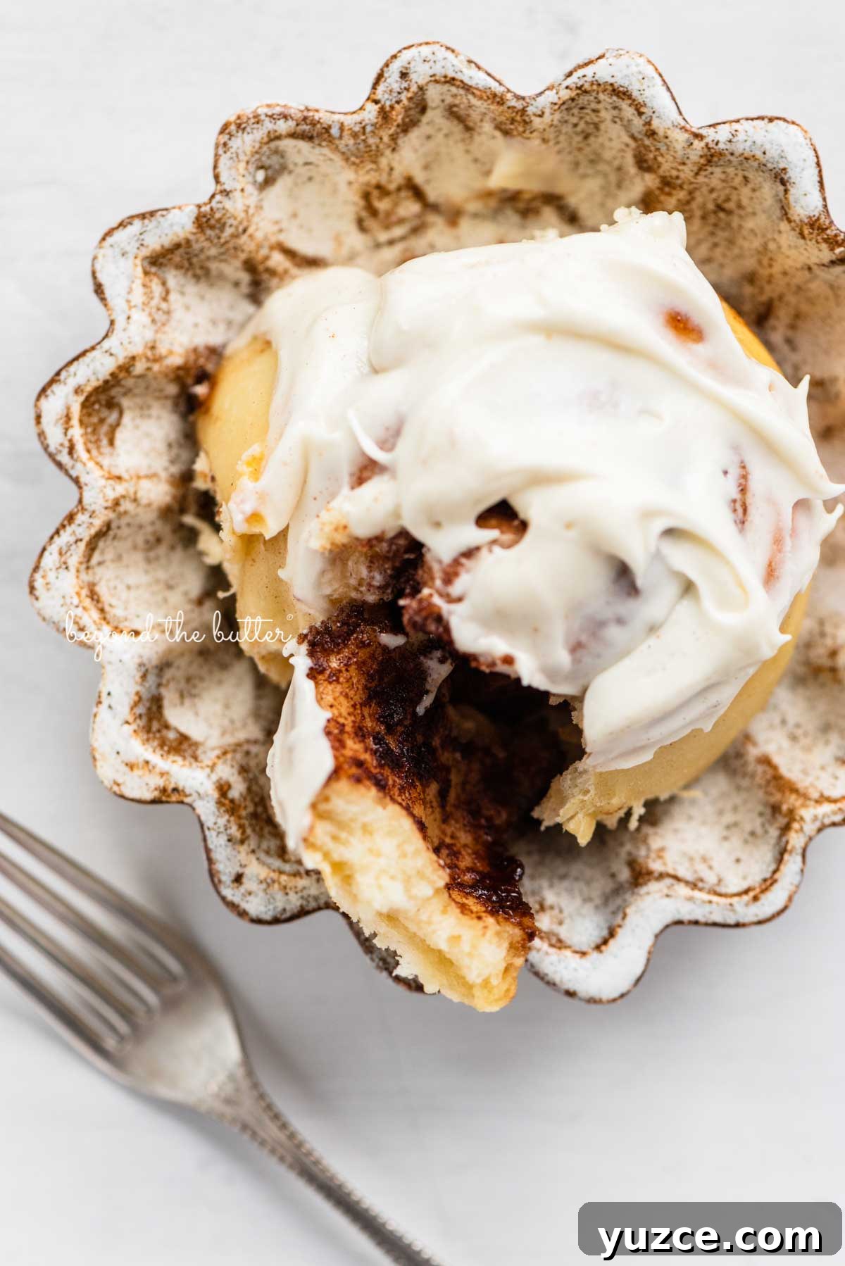 Cinnamon Rolls for Two: Small-Batch Recipe with Gooey Frosting 4 Cream Cheese frosting covered cinnamon roll on small ceramic dessert plate | © Beyond the Butter®