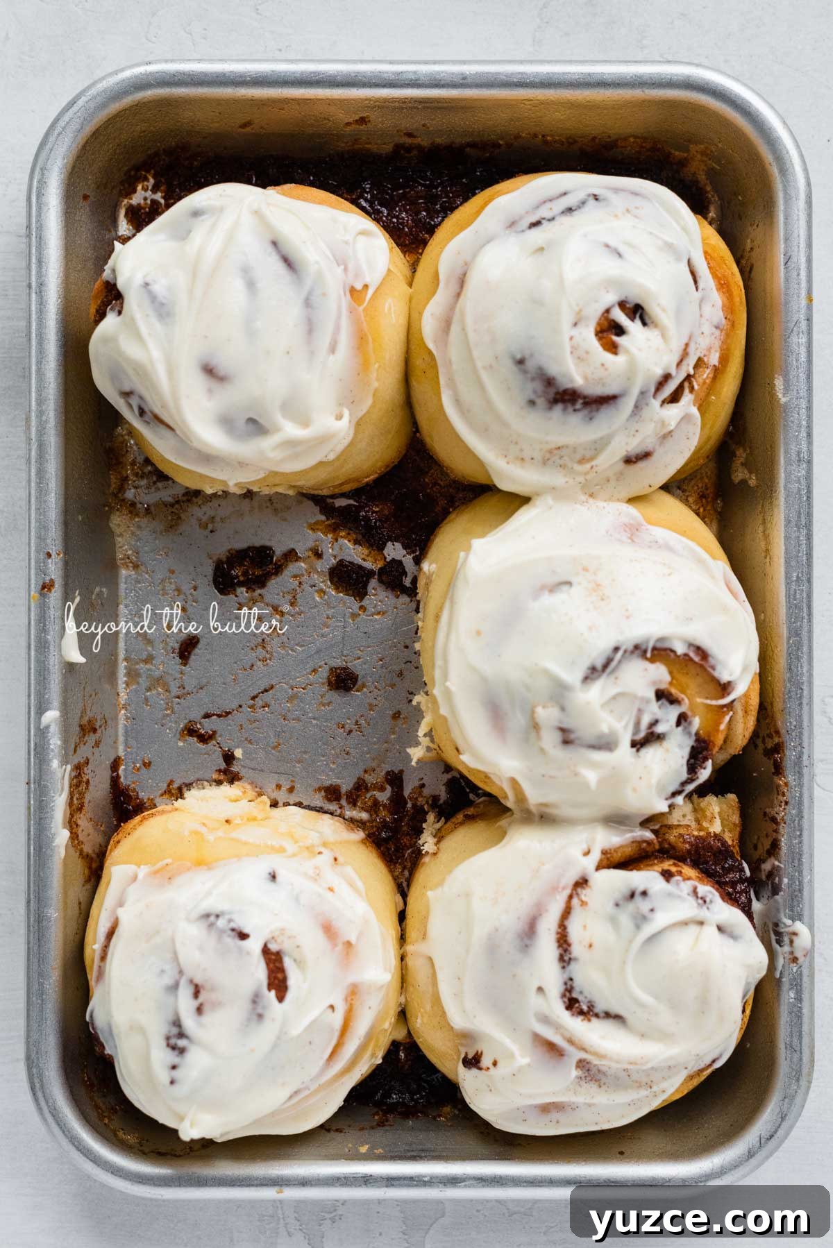 Cinnamon Rolls for Two: Small-Batch Recipe with Gooey Frosting 9 Just frosted small batch cinnamon rolls with one already eaten from BeyondtheButter.com | © Beyond the Butter®