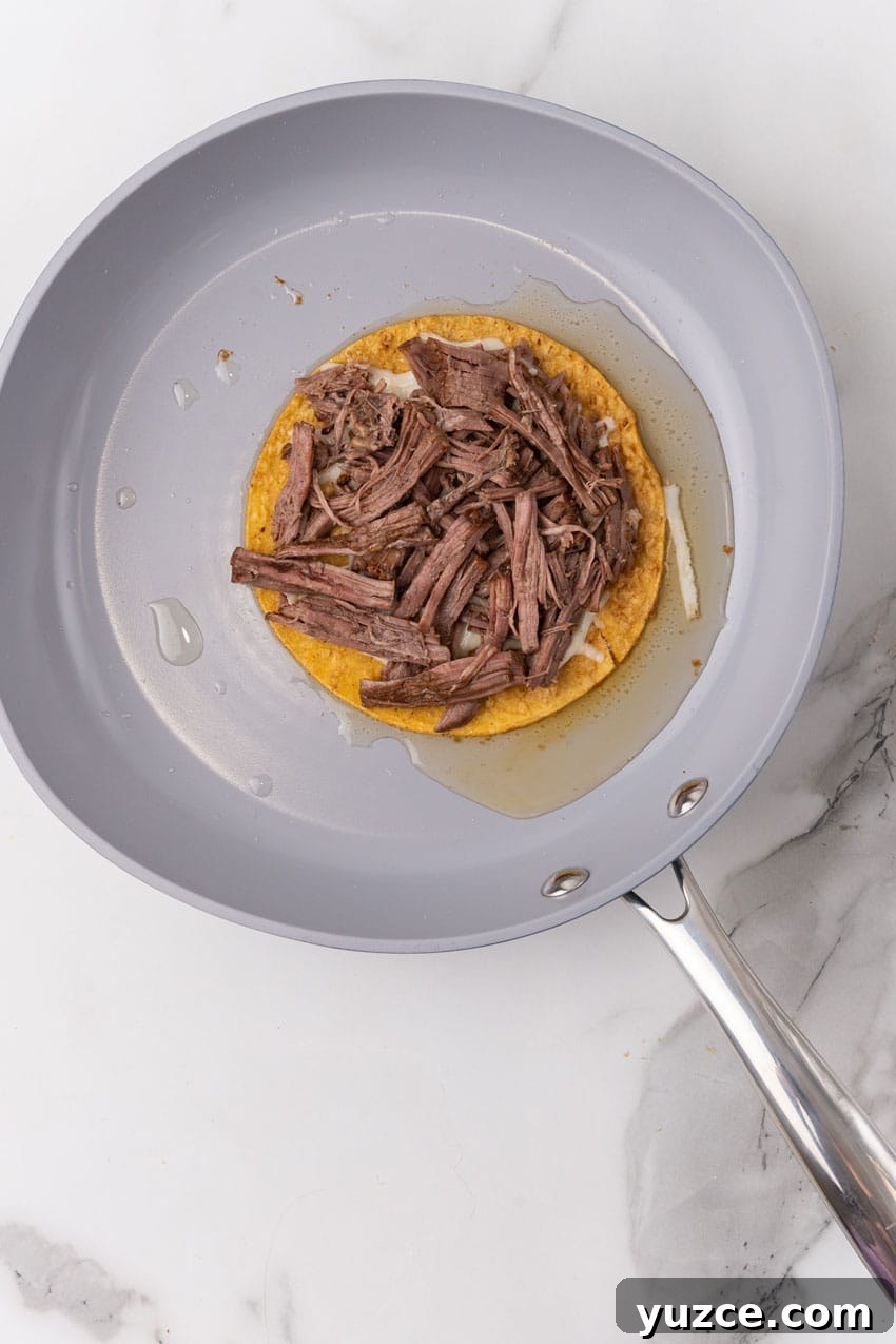 Instant Pot Birria Tacos Recipe: Flavorful Homemade Birria 10 a birria taco in oil in a large skillet