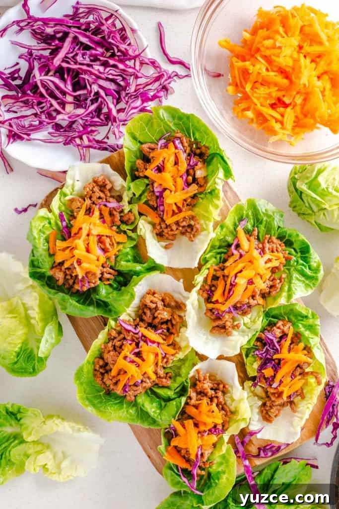 Ground Beef Lettuce Wraps with Hoisin Lime Sauce 8 Multiple beef lettuce wraps on a cutting board with lettuce, cabbage, and carrots around them.