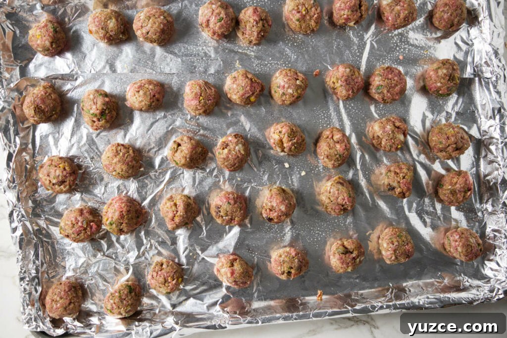 Moroccan Spiced Lamb Meatballs with Tomato Sauce 9 Raw lamb meatballs on a baking sheet.