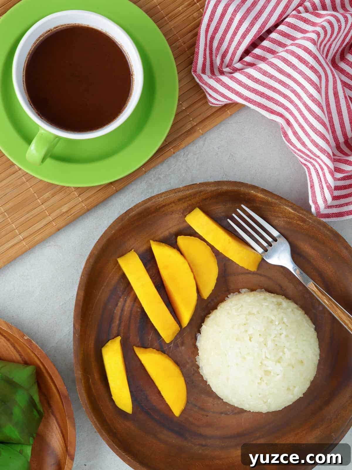 Puto Maya and Sikwate: Cebu's Sticky Rice Cake with Chocolate Tea 2 puto maya with sliced mangoes on a wooden plate and a cup of sikwate