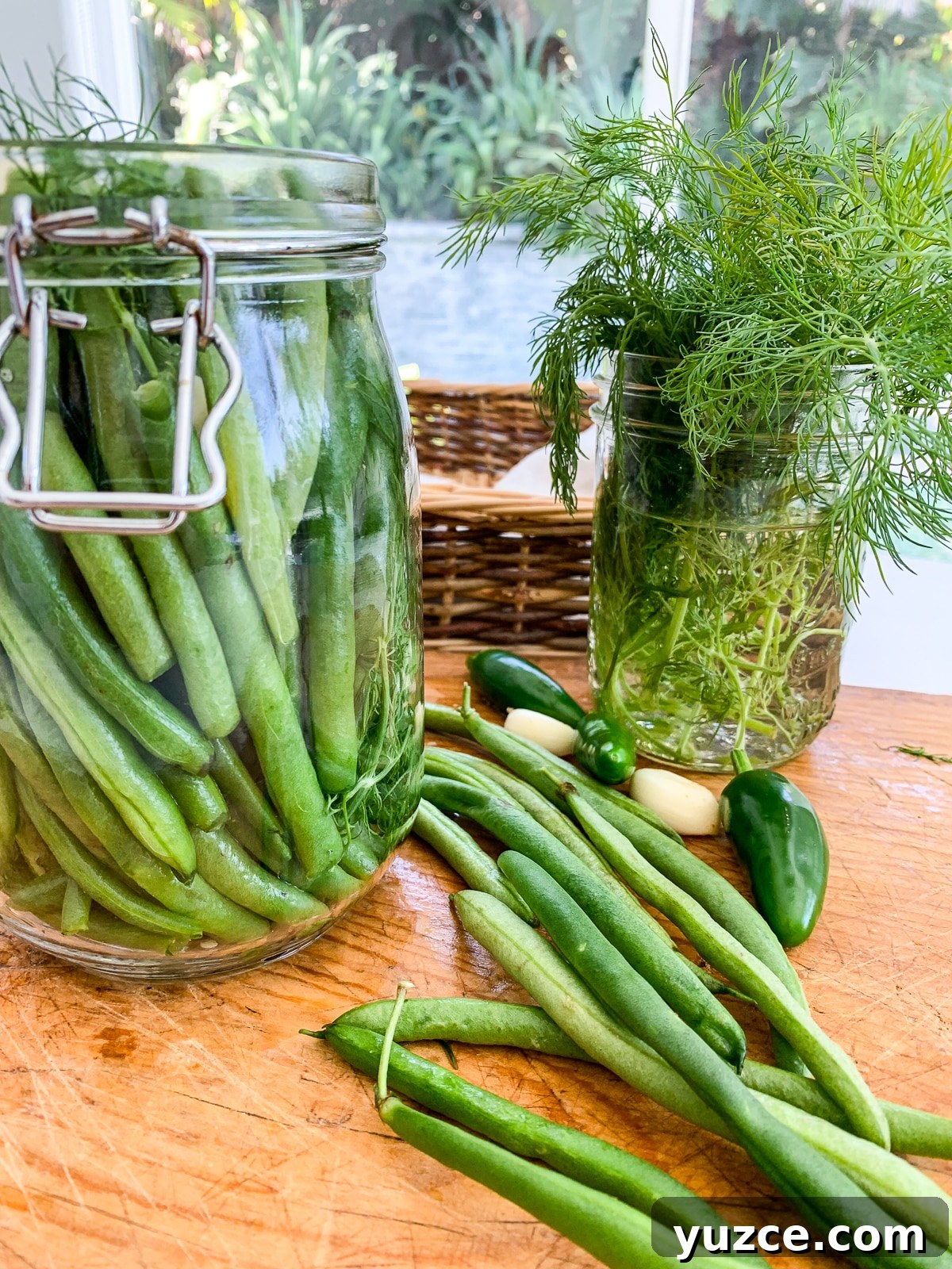 Dilly Pickled Green Beans Recipe: Classic Refrigerator Dilly Beans 12 A clear clamp jar filled with pickled green beans and ingredients on a cutting board.