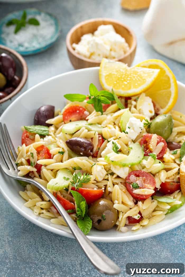Greek Orzo Salad with Feta, Cucumber & Lemon Dressing 2 White plate of greek orzo salad garnished with wedges of lemon