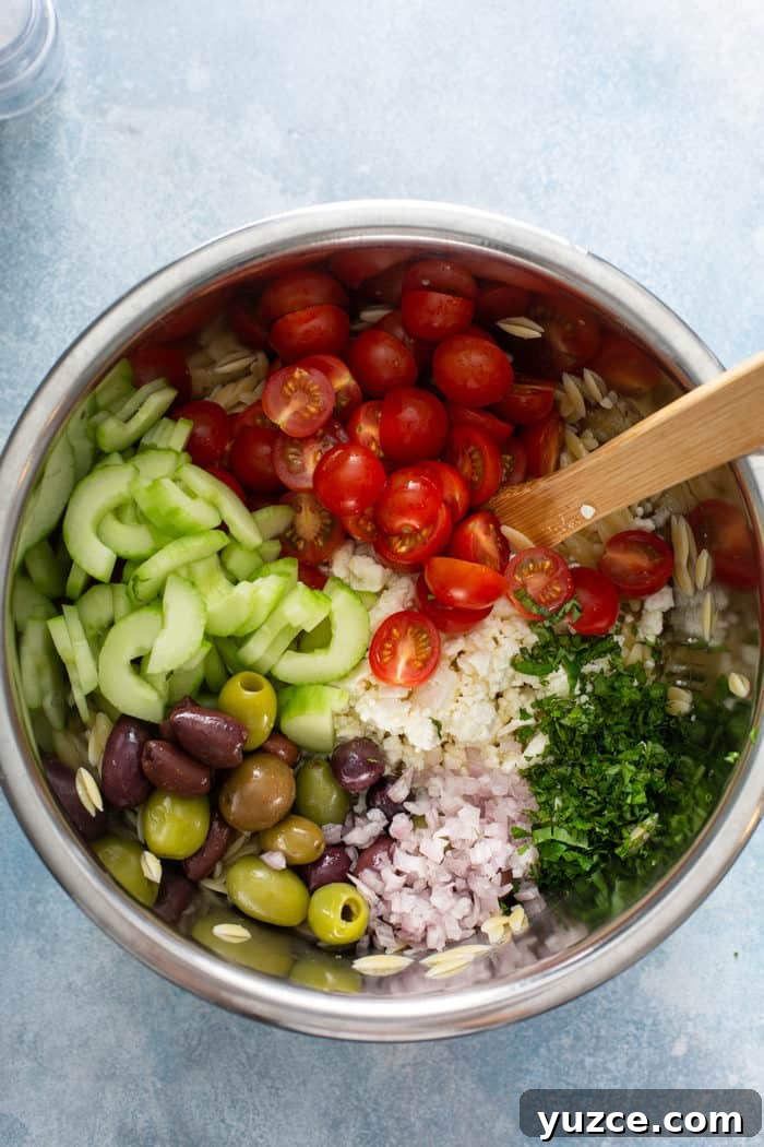 Greek Orzo Salad with Feta, Cucumber & Lemon Dressing 6 Vegetables and herbs for greek orzo salad in a mixing bowl, about to be mixed with cooked orzo
