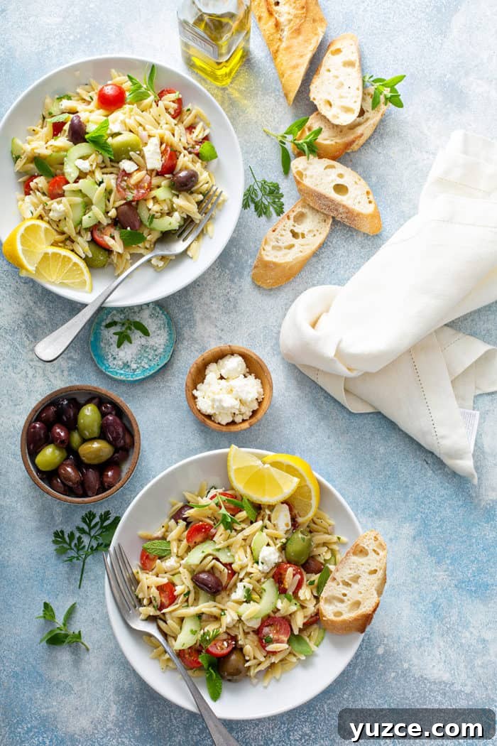 Greek Orzo Salad with Feta, Cucumber & Lemon Dressing 10 Greek orzo salad in two small white bowls surrounded by olives, feta, and slices of baguette