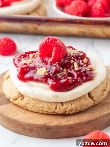 Raspberry pie filling on top of cheesecake cookie on white plate.