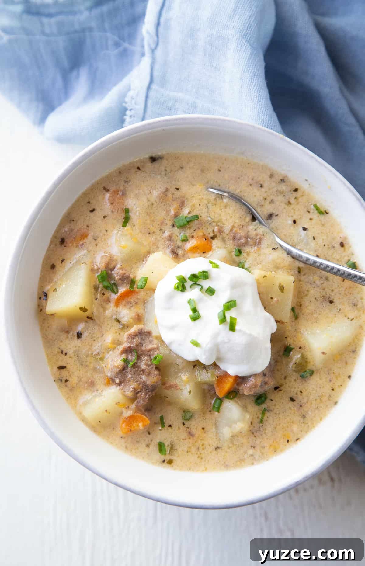 Slow Cooker Cheeseburger Soup Recipe for Comforting Weeknights 2 white bowl of crockpot cheeseburger soup with a blue napkin.