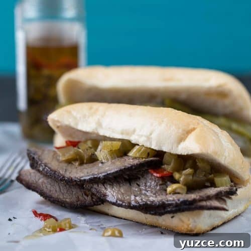 Italian beef sandwich on a soft roll, sitting on white parchment paper.