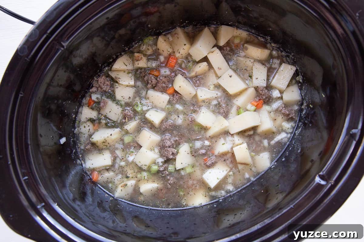 Slow Cooker Cheeseburger Soup Recipe for Comforting Weeknights 5 beef, potatoes, and broth in a crockpot.