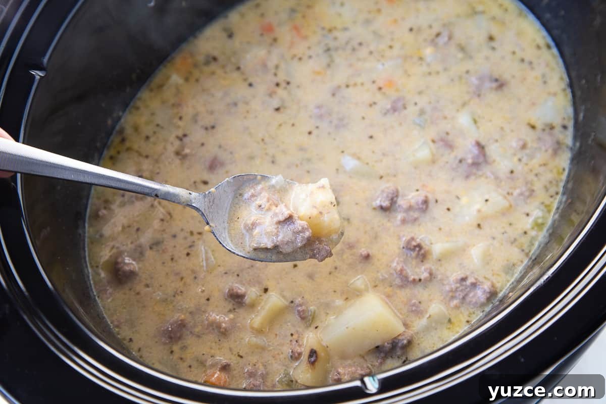 Slow Cooker Cheeseburger Soup Recipe for Comforting Weeknights 7 spoon with a scoop of cheeseburger soup on it.