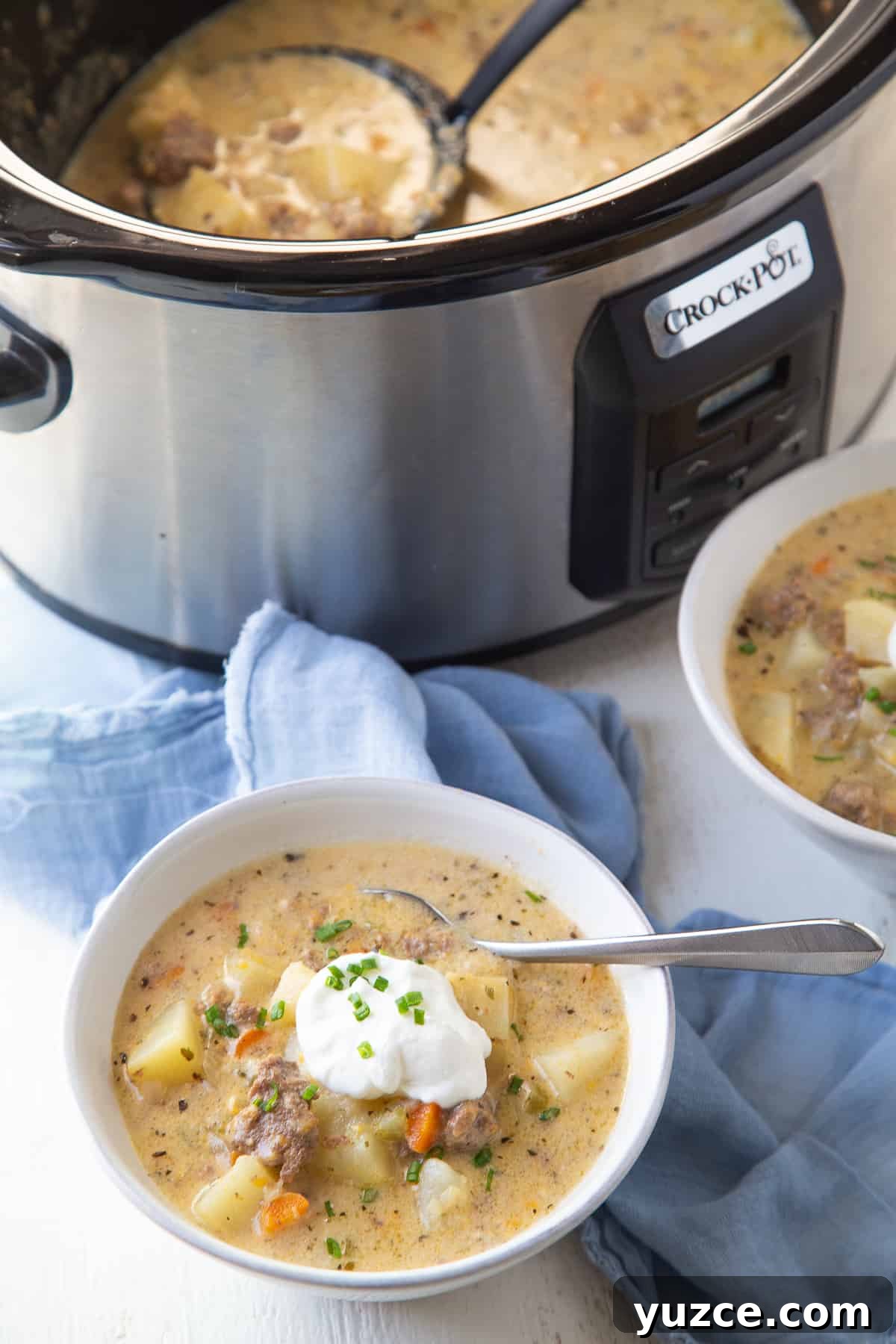 Slow Cooker Cheeseburger Soup Recipe for Comforting Weeknights 8 bowl of cheeseburger soup next to a crockpot full of more soup.