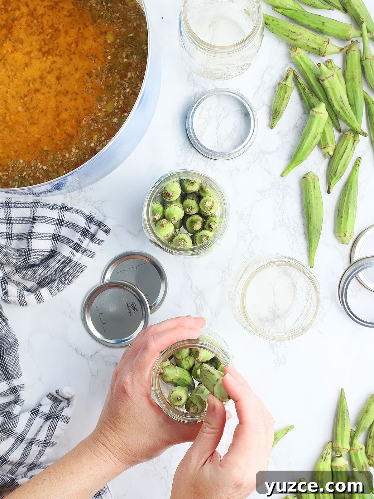 Tangy Spicy Pickled Okra Recipe for Bold Flavor 7 Hands packing fresh okra into mason jars.