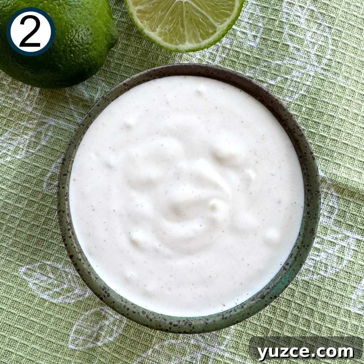 Mixture of mayonnaise, sour cream, lime juice, pressed garlic, and cayenne pepper in a small bowl.