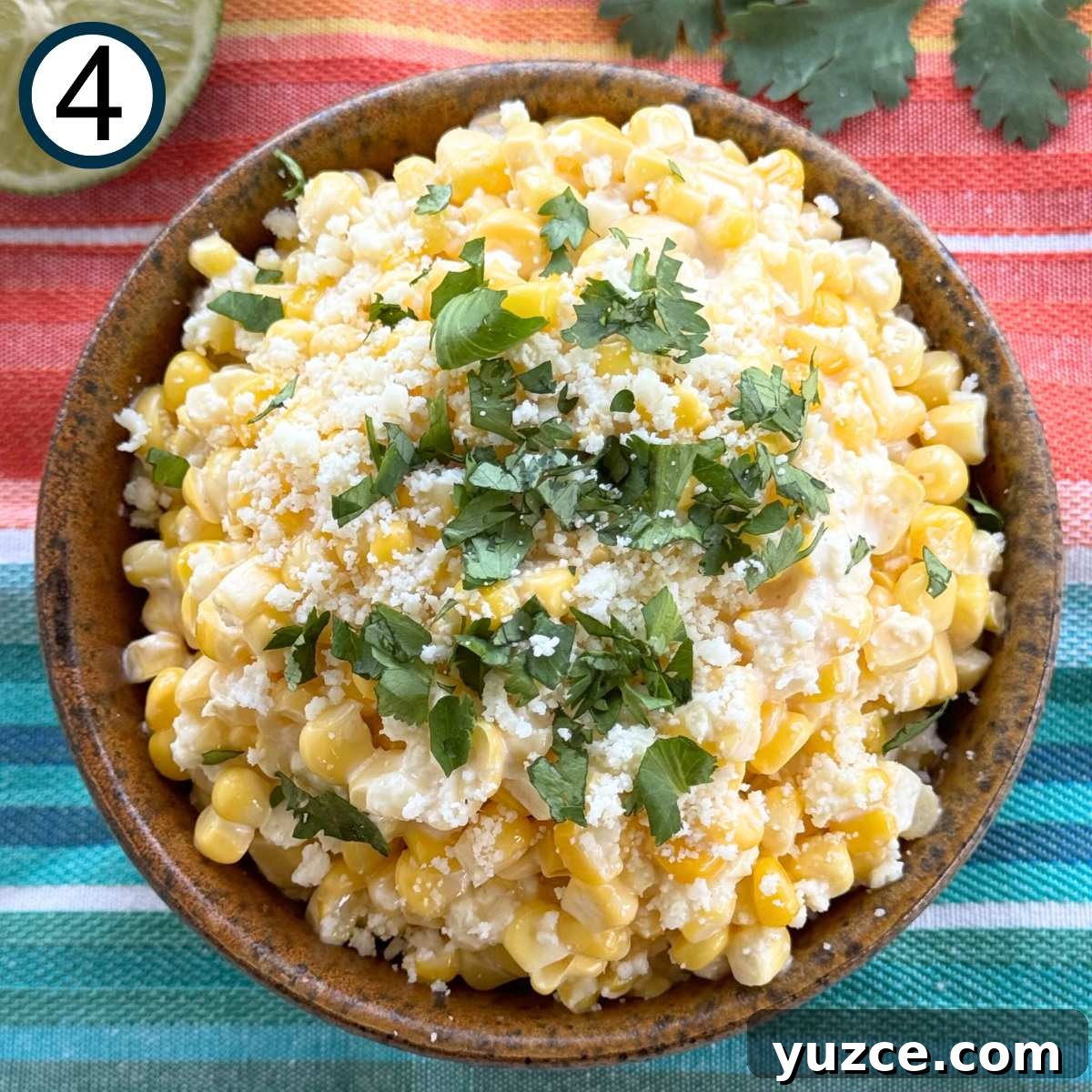 Mexican street corn in a brown serving bowl topped with Cotija cheese and chopped cilantro.