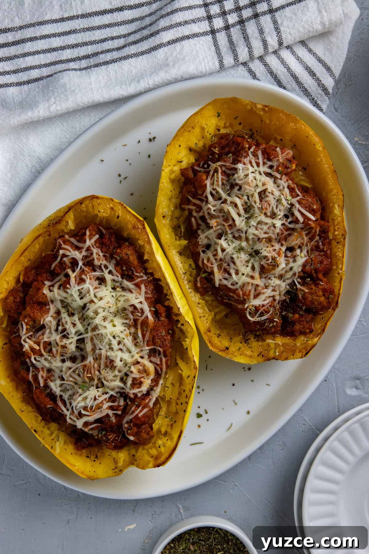 Cheesy Stuffed Spaghetti Squash Recipe with Italian Sausage 2 Two roasted spaghetti squash halves topped with spaghetti sauce and mozzarella cheese.