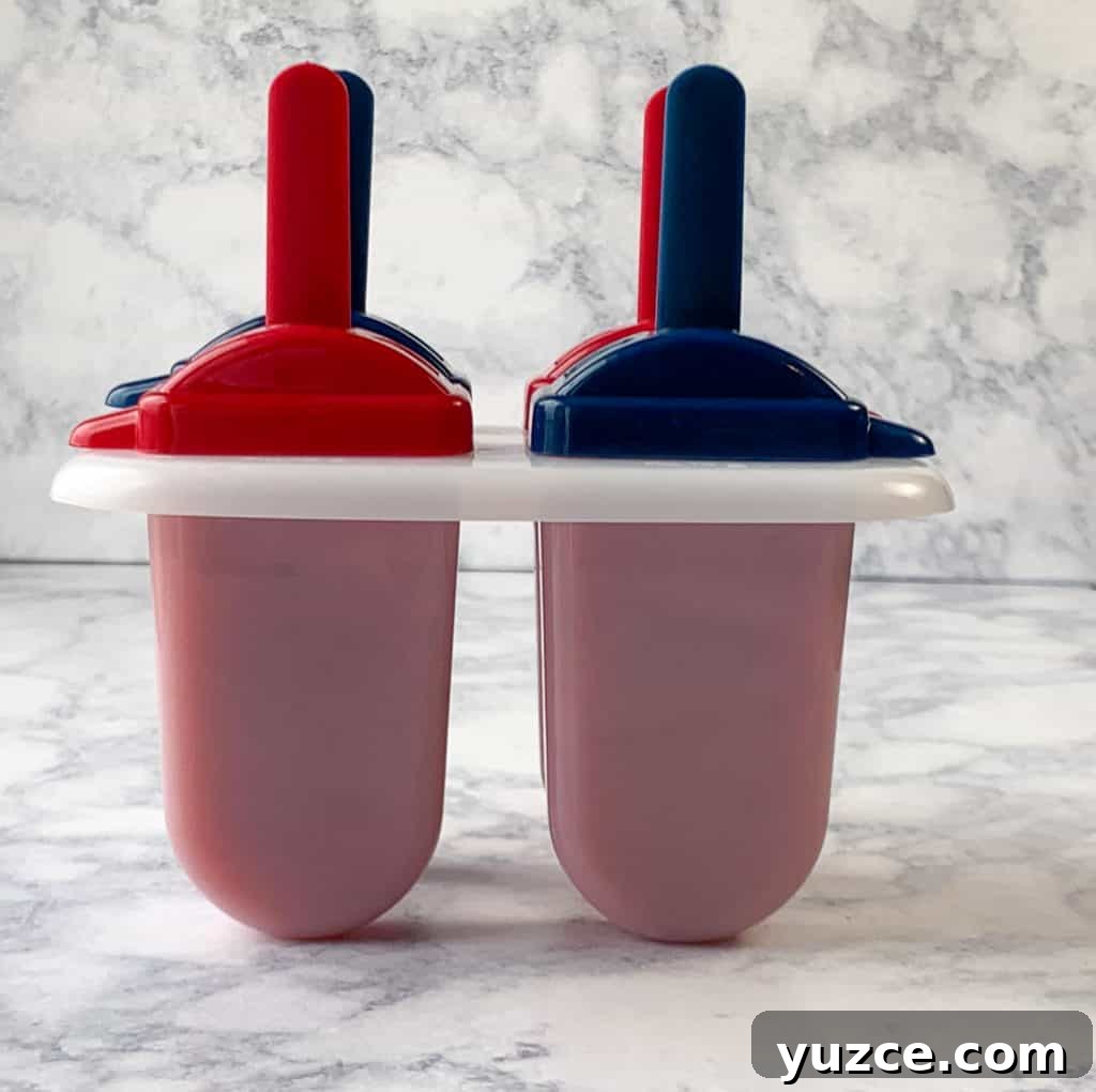 Homemade fruit popsicles in popsicle molds on white counter
