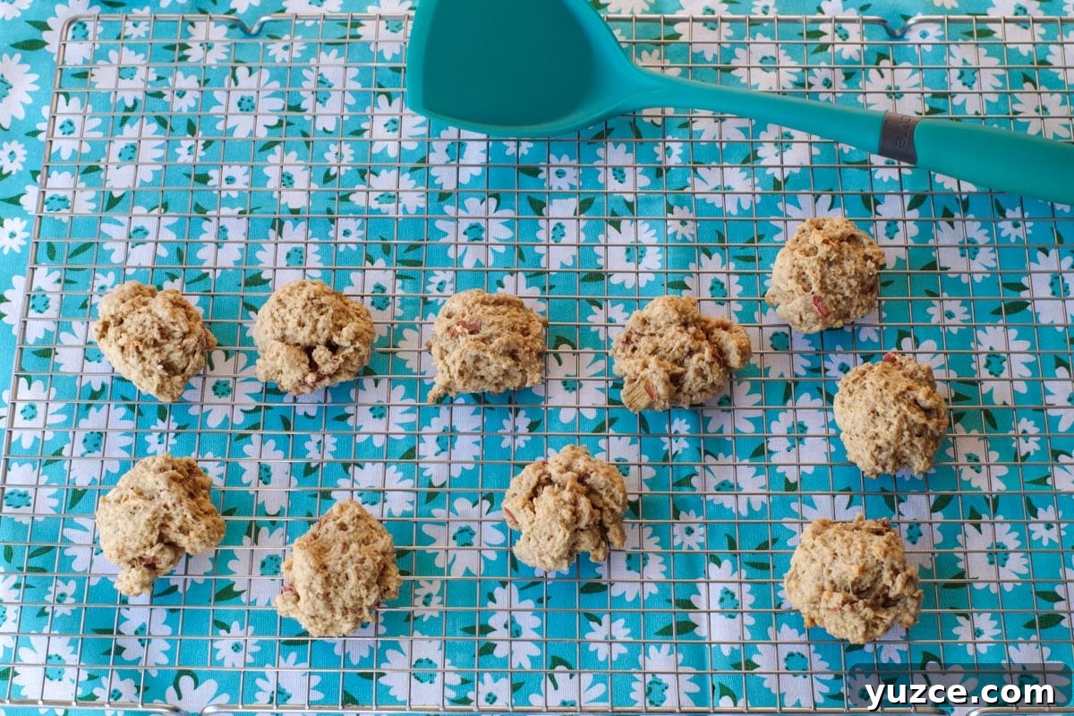 Brown Sugar Oatmeal Cookies with Tangy Rhubarb 14 rhubarb cookies on a wire cooking rack, with a turquoise spatula and a flowered tea towel under the rack