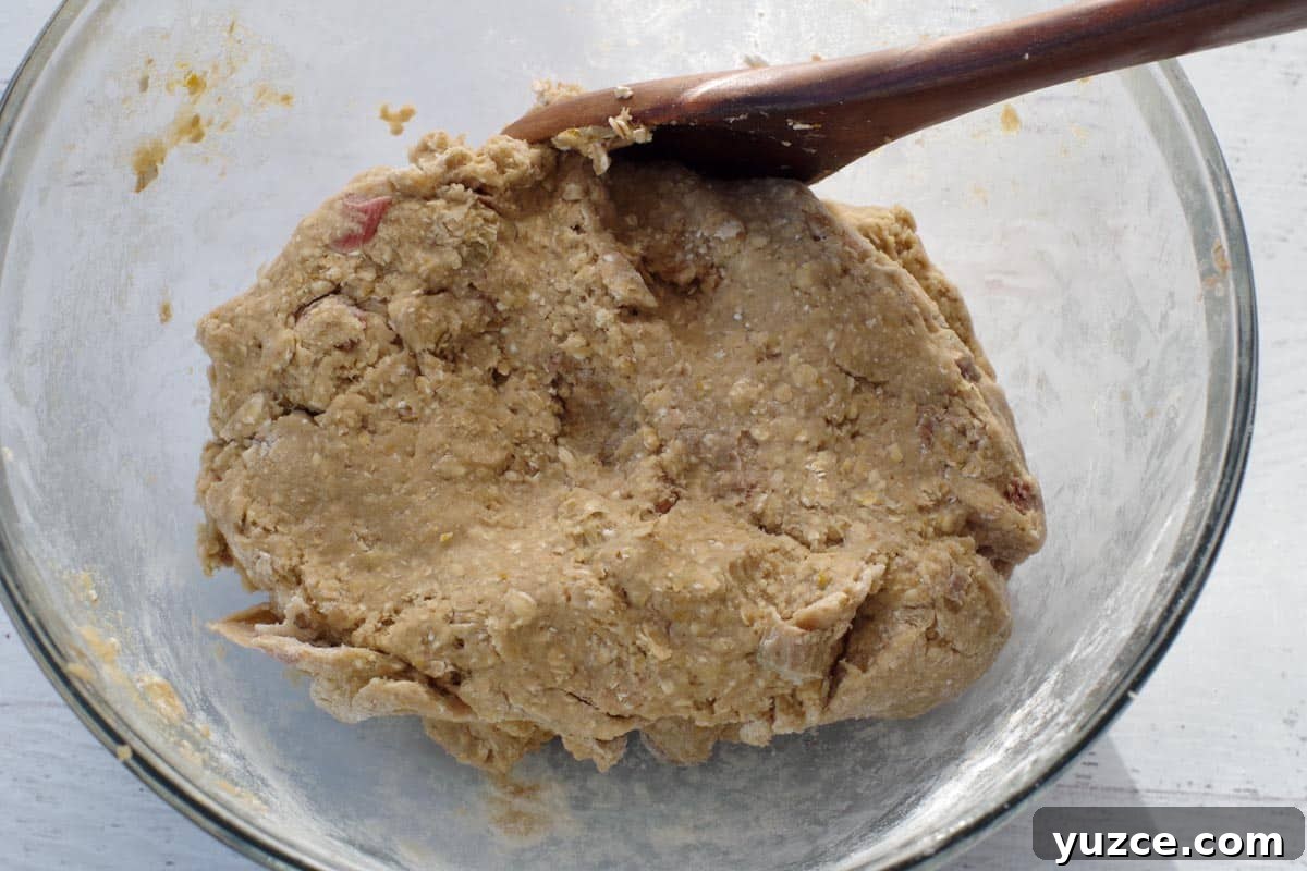 Brown Sugar Oatmeal Cookies with Tangy Rhubarb 10 rhubarb cookie dough in a glass bowl with a dark brown wooden spoon