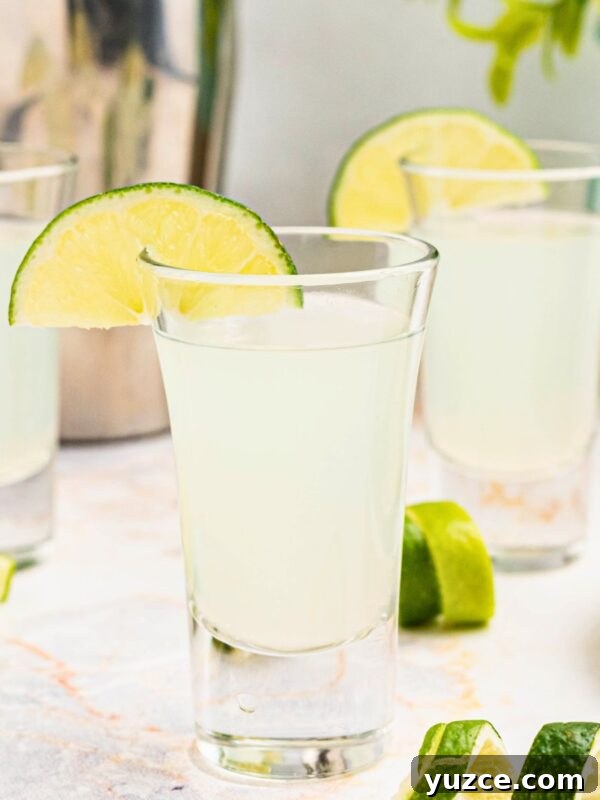 Classic Southern Sweet Potato Pie Recipe — Step-by-Step Guide 12 Cold Kamikaze shots in shot glasses with lime wedges and lime curls on a marble table in front of a cocktail shaker.