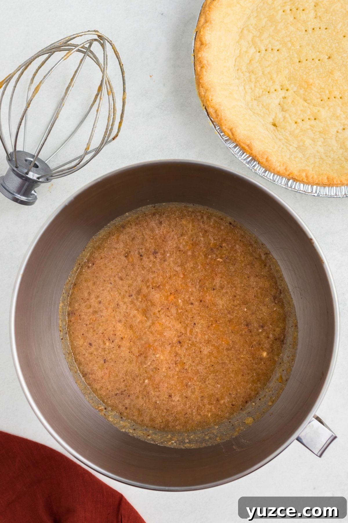 Classic Southern Sweet Potato Pie Recipe — Step-by-Step Guide 5 Mashed sweet potatoes mixed with other ingredients in a silver mixing bowl.