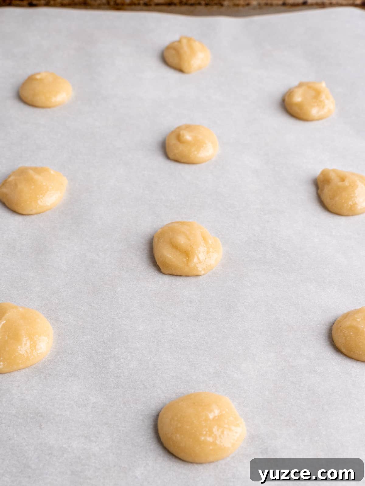 4-Ingredient Lace Cookies Recipe: Crispy Thin Cookie Delight 6 Drops of lace cookie dough on a baking sheet with parchment paper.