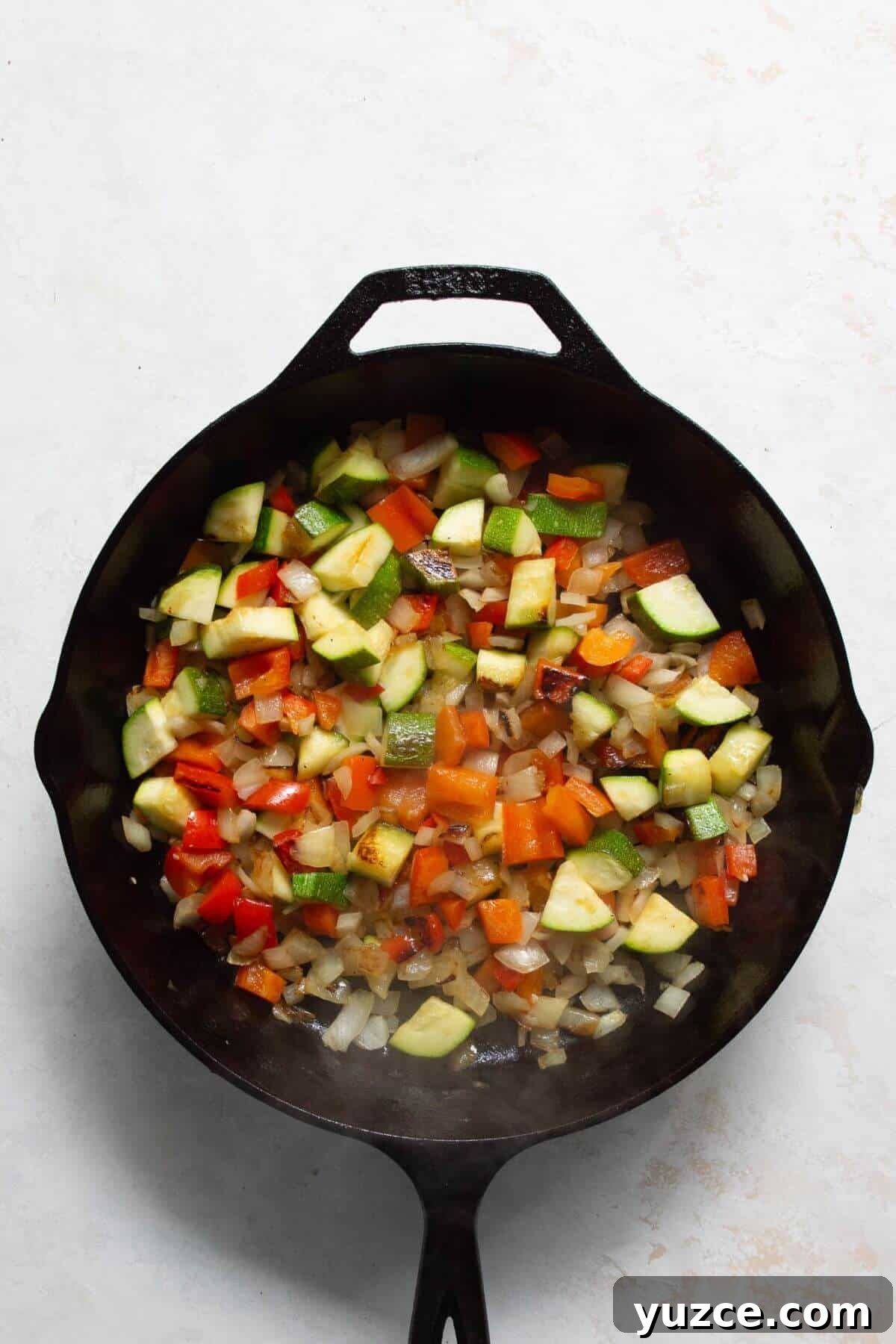 Perfect Shakshuka Recipe: Flavorful One-Pan Eggs and Tomatoes 4 Sautéing onion, bell pepper, and zucchini in a cast iron skillet for shakshuka